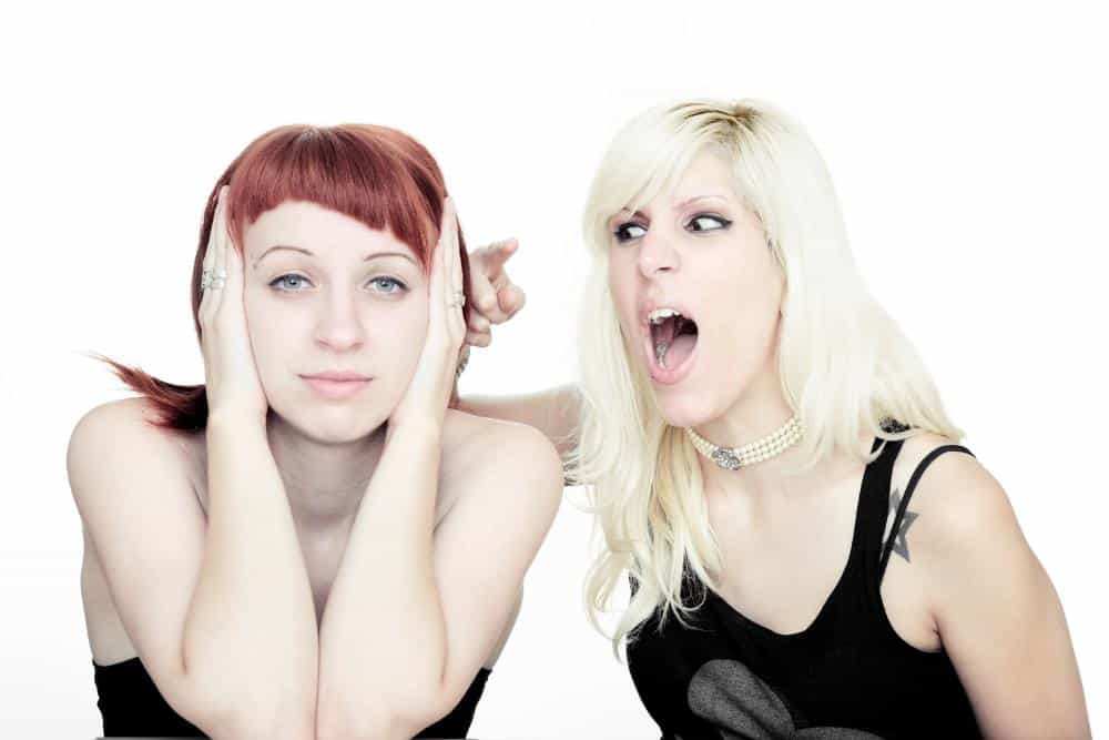 A woman screaming at another woman who is covering her ears