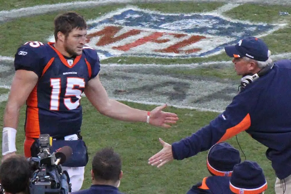 Tim Tebow shaking hands with his coach after a well-executed play