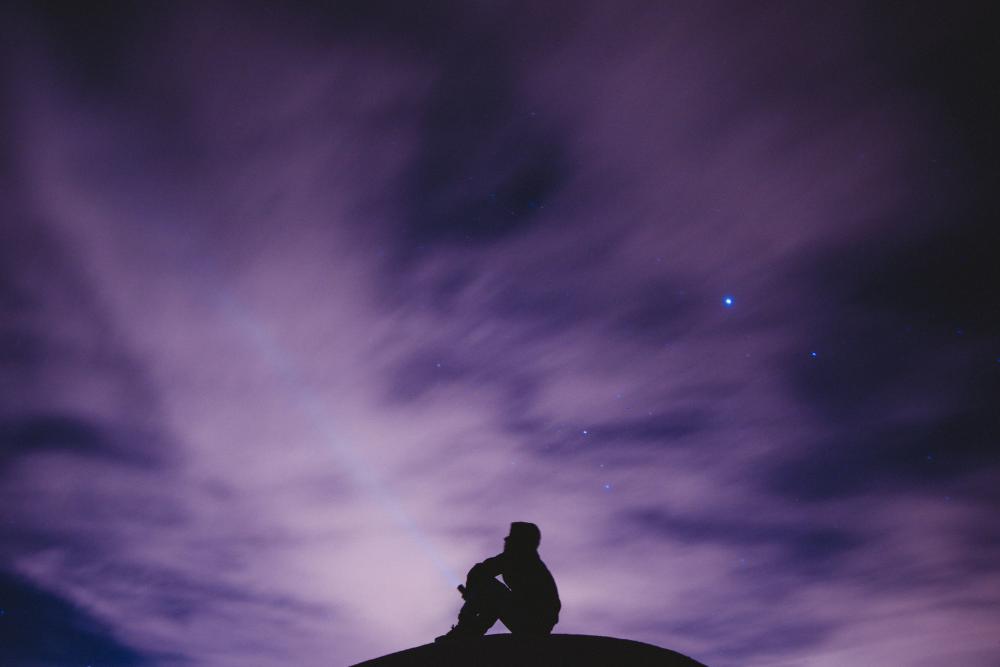 person sitting under the sky alone
