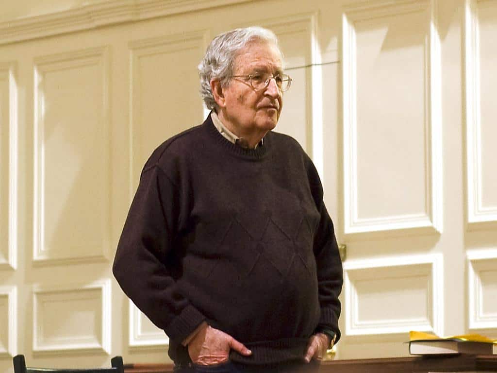 Noam Chomsky standing with his hands in pockets