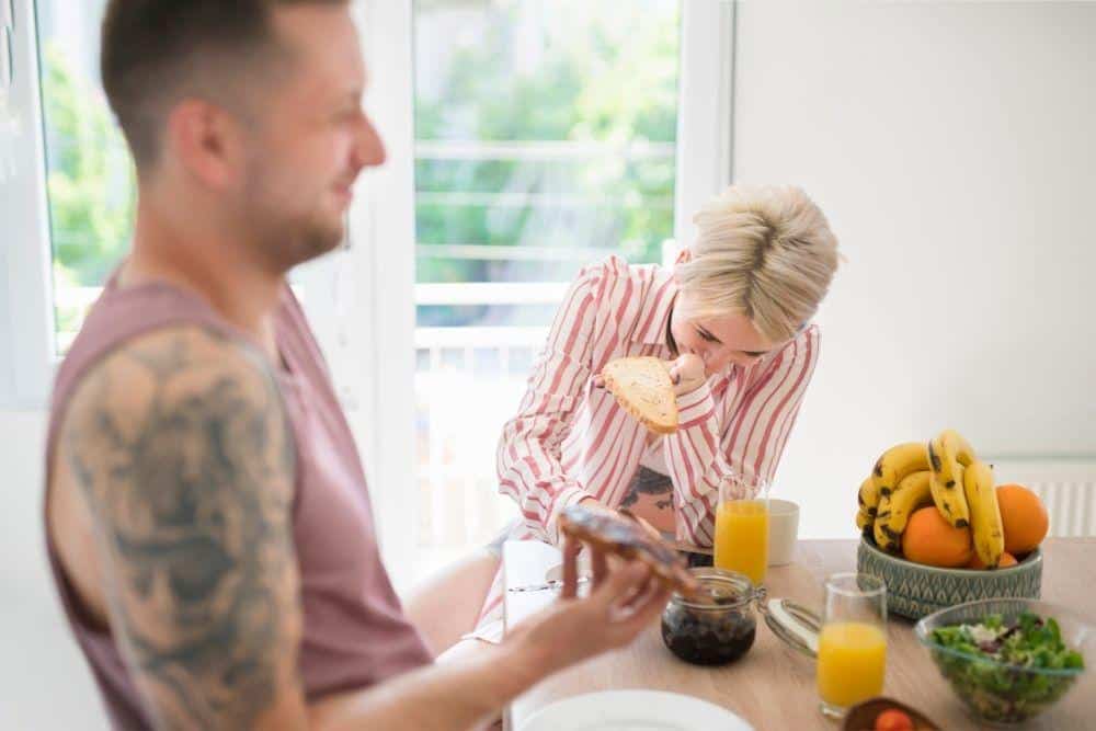 Two persons laughing while making breakfast