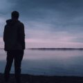 a man standing near a lake alone