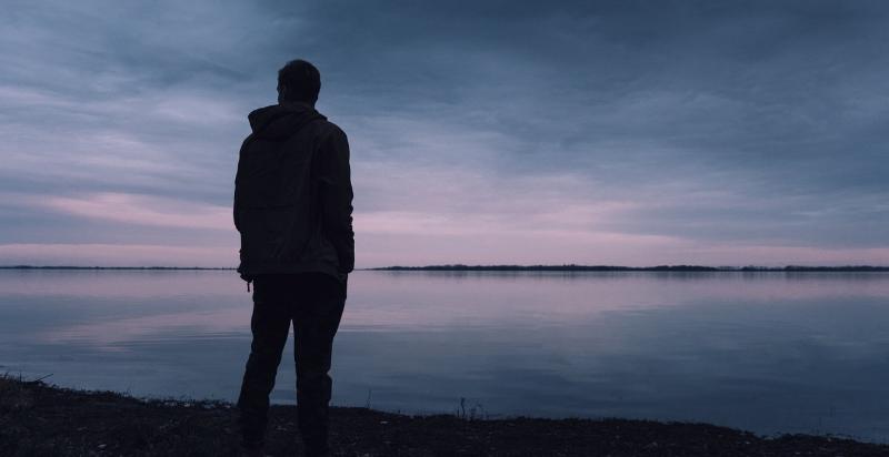a man standing near a lake alone