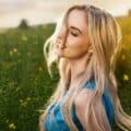 A young blonde woman standing in green grass