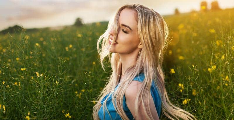 A young blonde woman standing in green grass