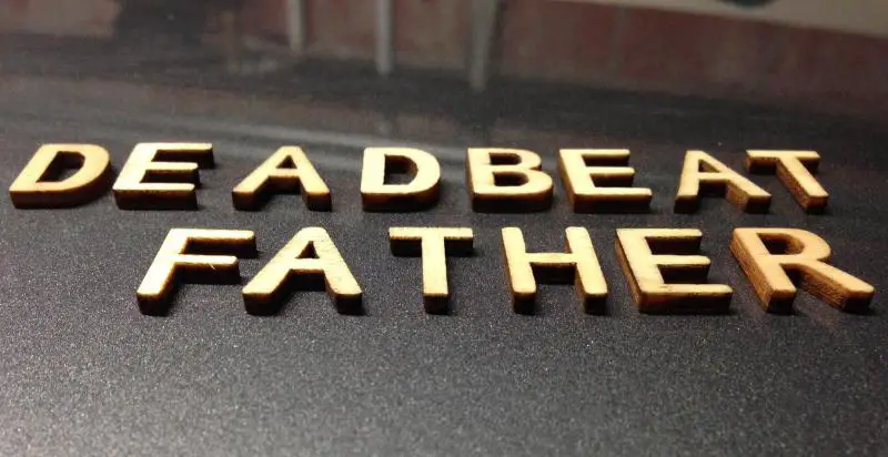 deadbeat father written with wooden letters on a black surface