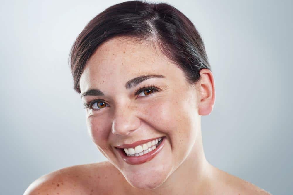 A freckled woman smiling