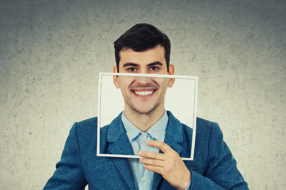 A man holding up a picture of him smiling