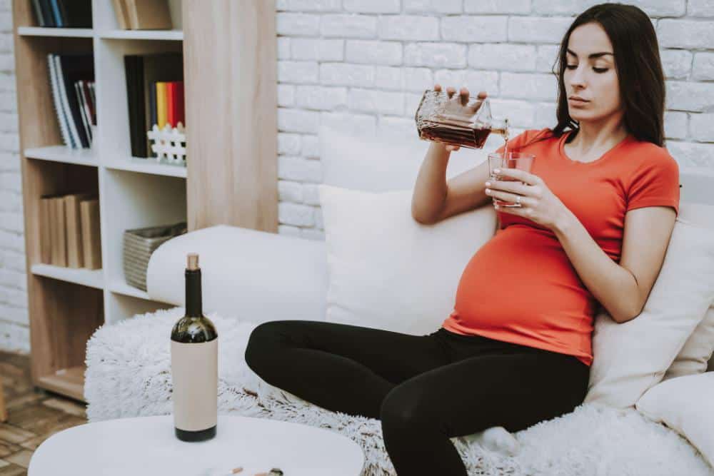 A pregnant woman pouring herself a drink