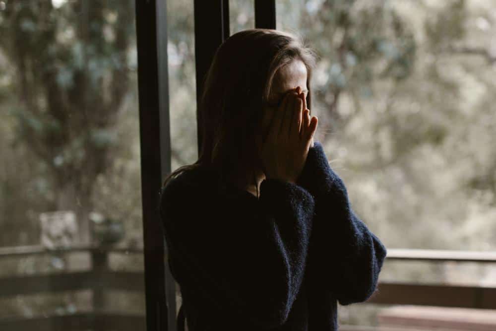 a woman standing with her hands on her face