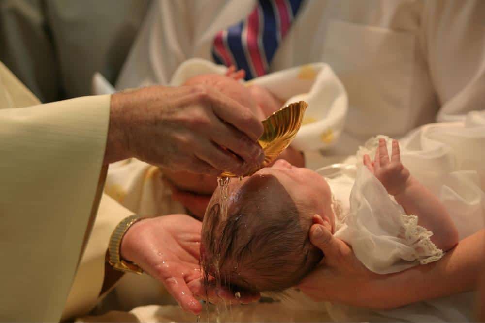 A baby getting baptized by a priest 